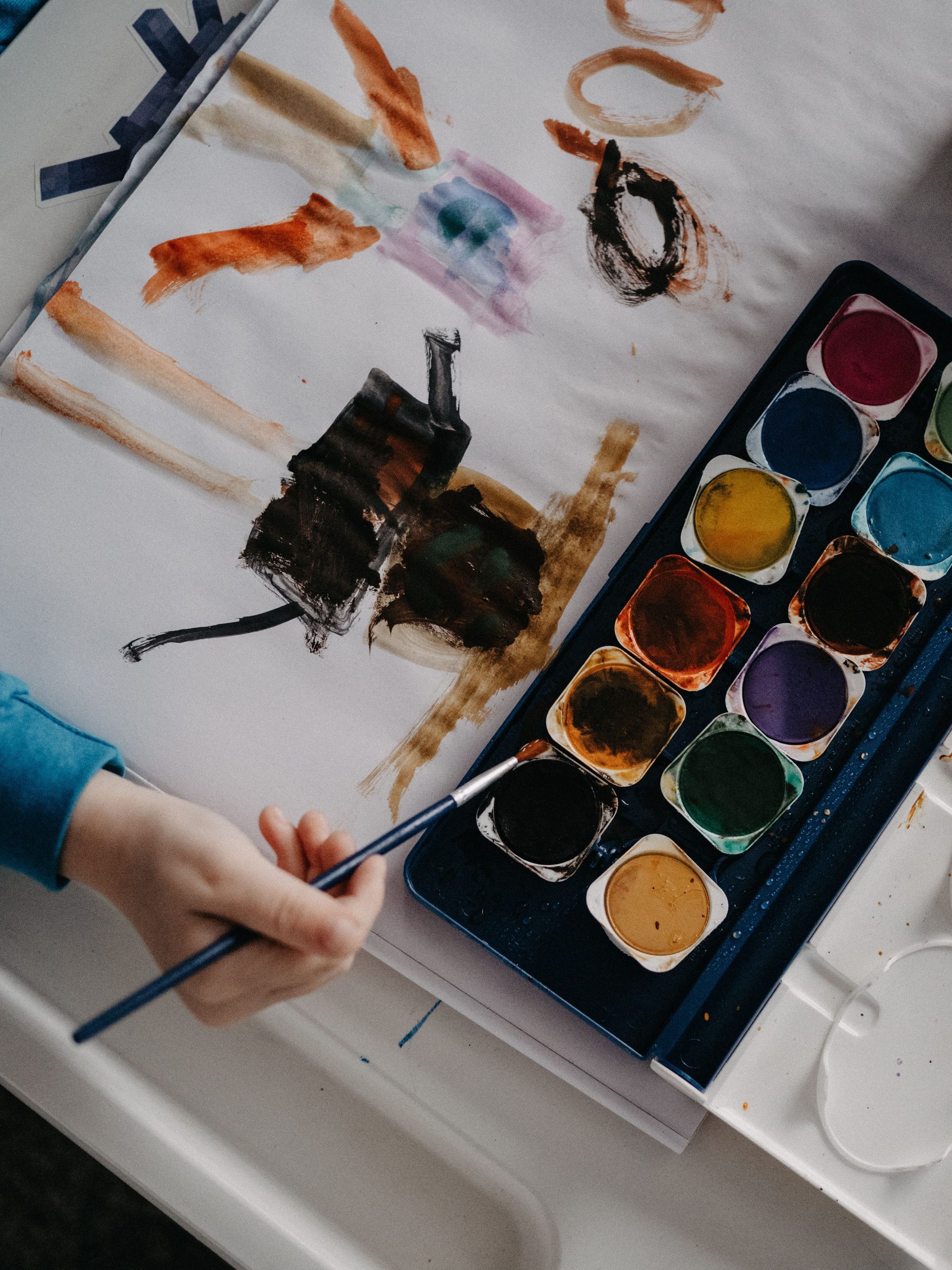 A child paints abstract art using vibrant watercolors at a table.